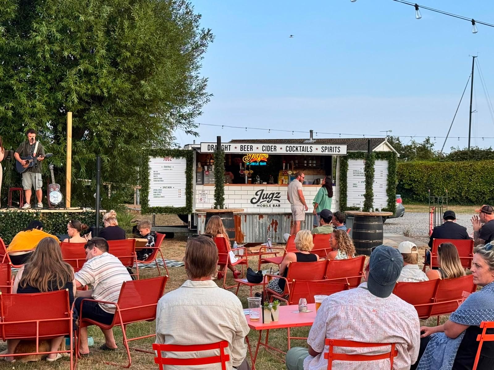 Seating and tables beside the Jugz Mobile Bar at an outdoor event