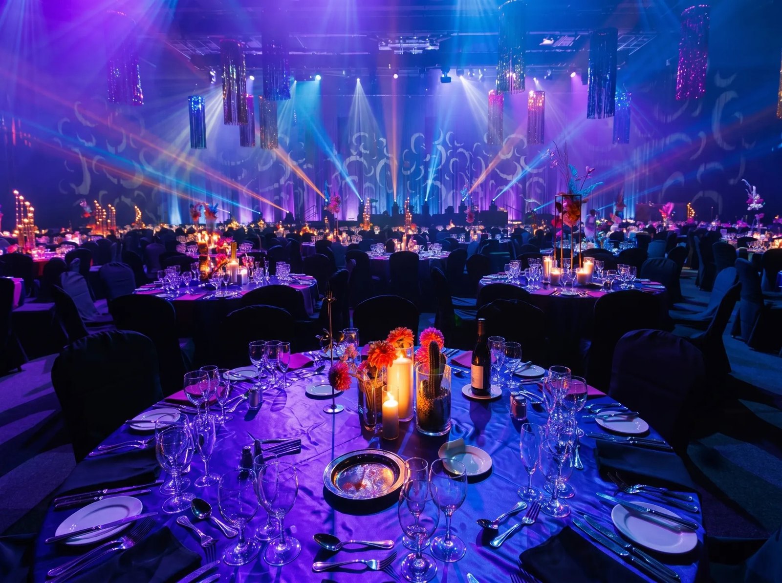 Gala dinner tables set under coloured stage lighting