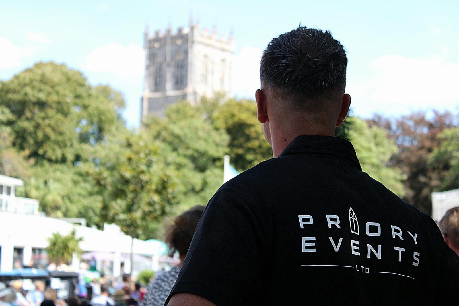 Priory Events crew member watching a village event beside a church