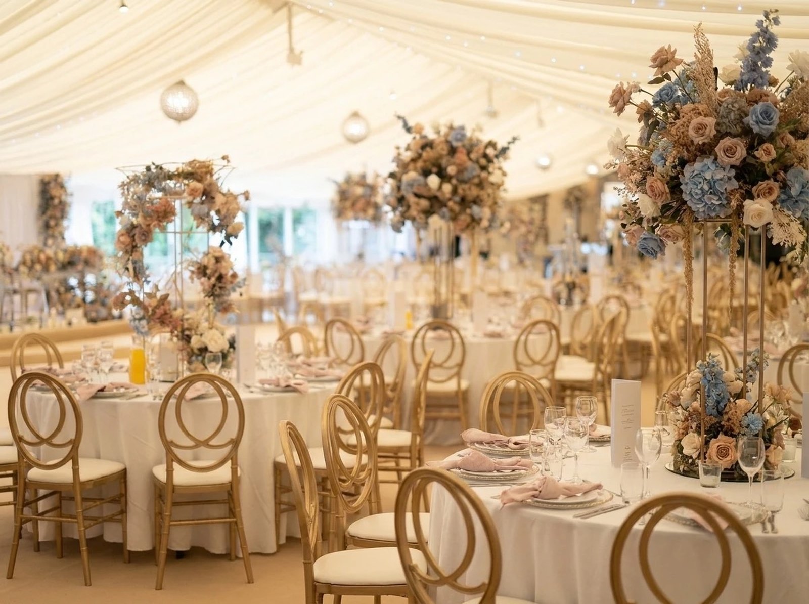 Wedding reception tables inside a marquee with floral centrepieces