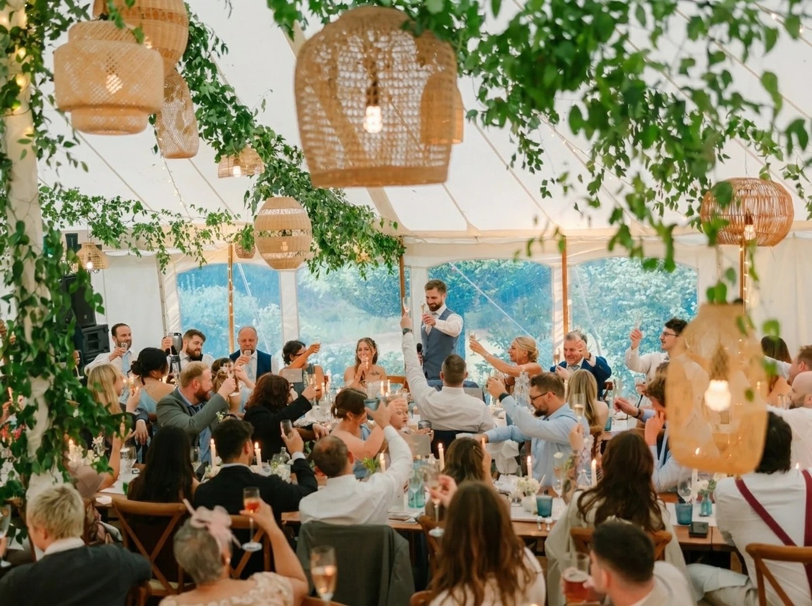 Wedding guests raising a toast during speeches inside a marquee